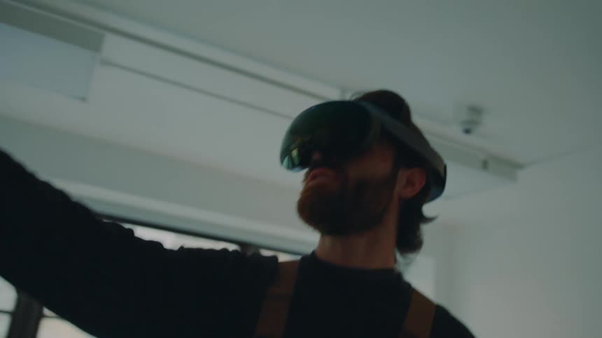 Man standing in empty room with view of another apartment building interacts using vr goggles