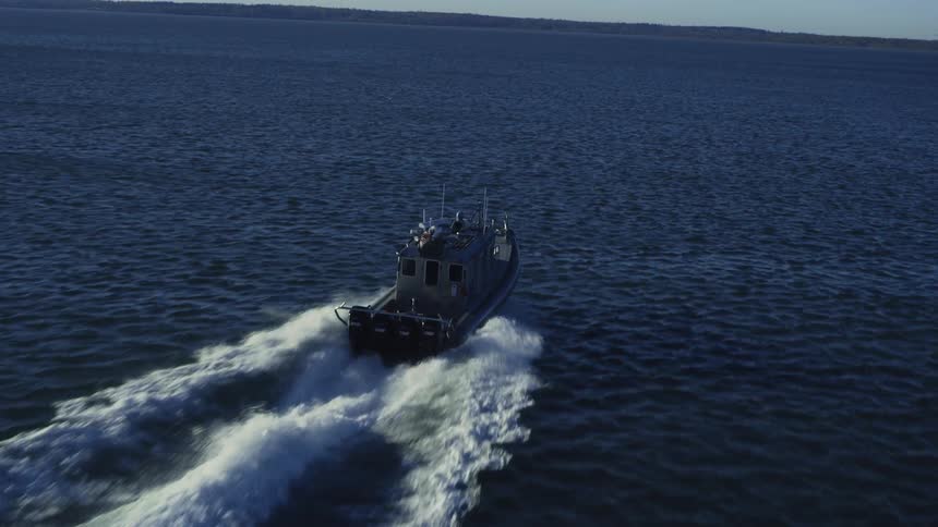 Motorboat speeds across ocean with coast in the background as radar antenna spins