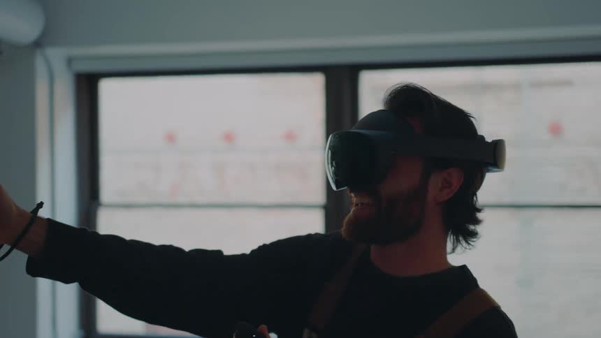 A man laughs while playing a virtual reality game