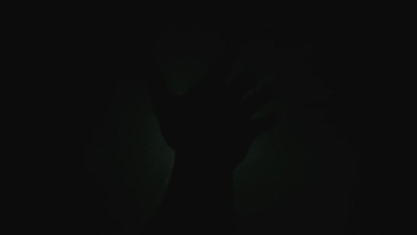 A man puts his hand up over a projector light