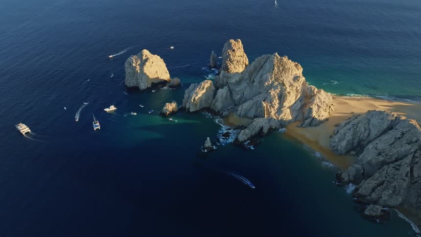 Boats are driving near an island in the ocean water