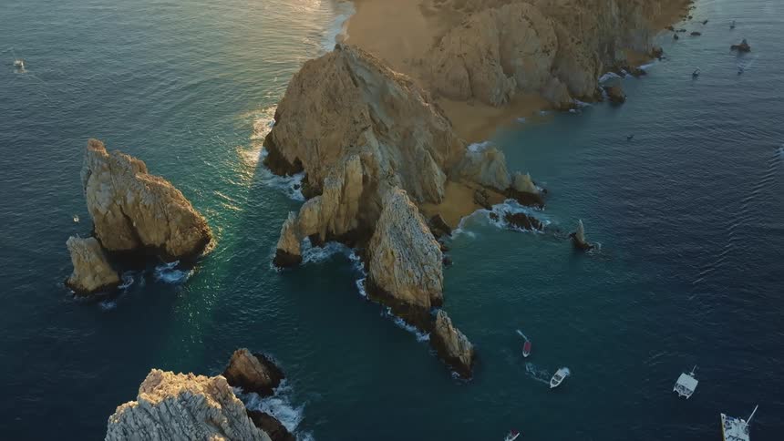 Aerial view of promontories in front of a narrow piece of land that projects from a coastline into the sea