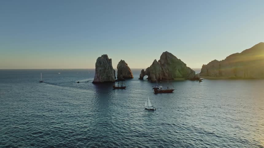 Boats are driving on ocean water while the sun is setting