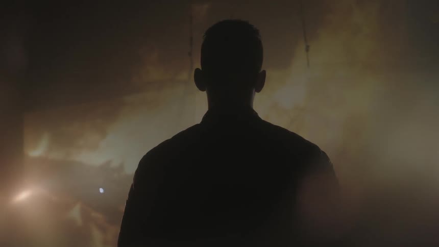A man watches a fire projected on a wall