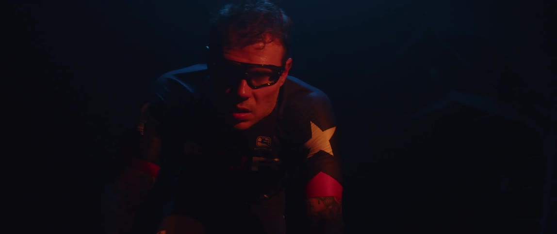 Man sweats profusely while exercising on stationary bike in dark room