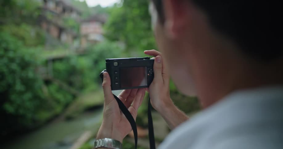 A man uses a digital camera to take a photograph of a river