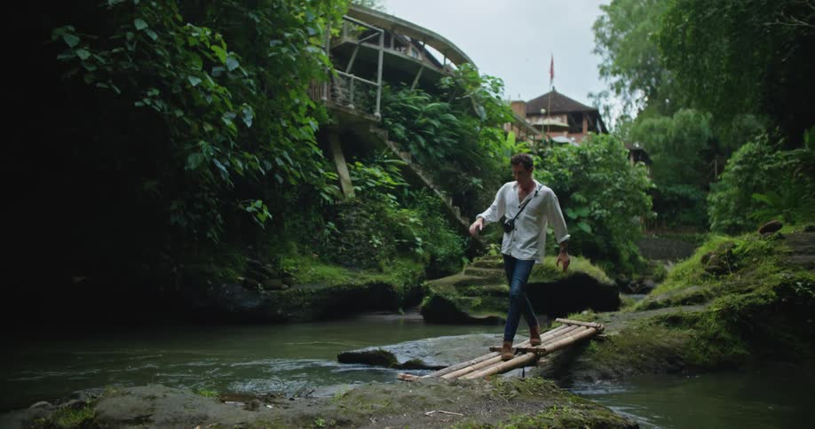 A man crosses the stream by the hills