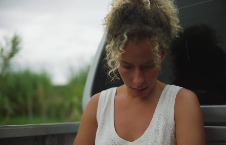 A woman pets her dog while sitting in the back of a pickup truck