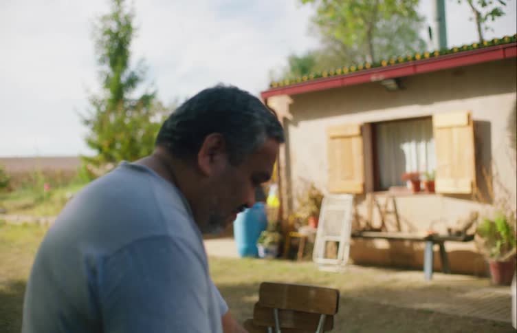 A man dries dishes outside a home as others set up for a party