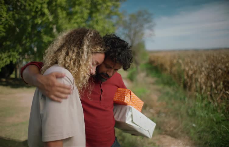 Friends console each other with a hug near a field on a farm