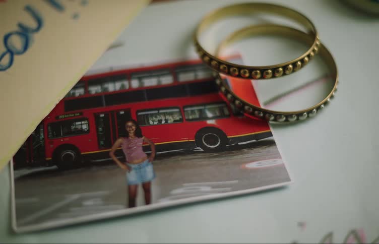 A portrait of a woman in front of a double decker bus sits on a table with two rings