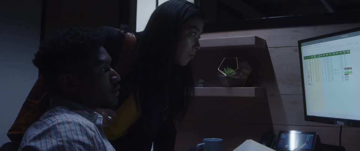 Colleagues compare paperwork to a spreadsheet on a computer