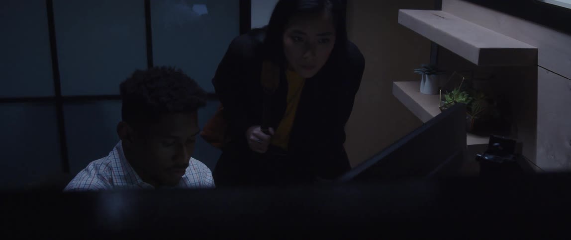 A woman stands at her colleagues desk while they look at a computer screen together