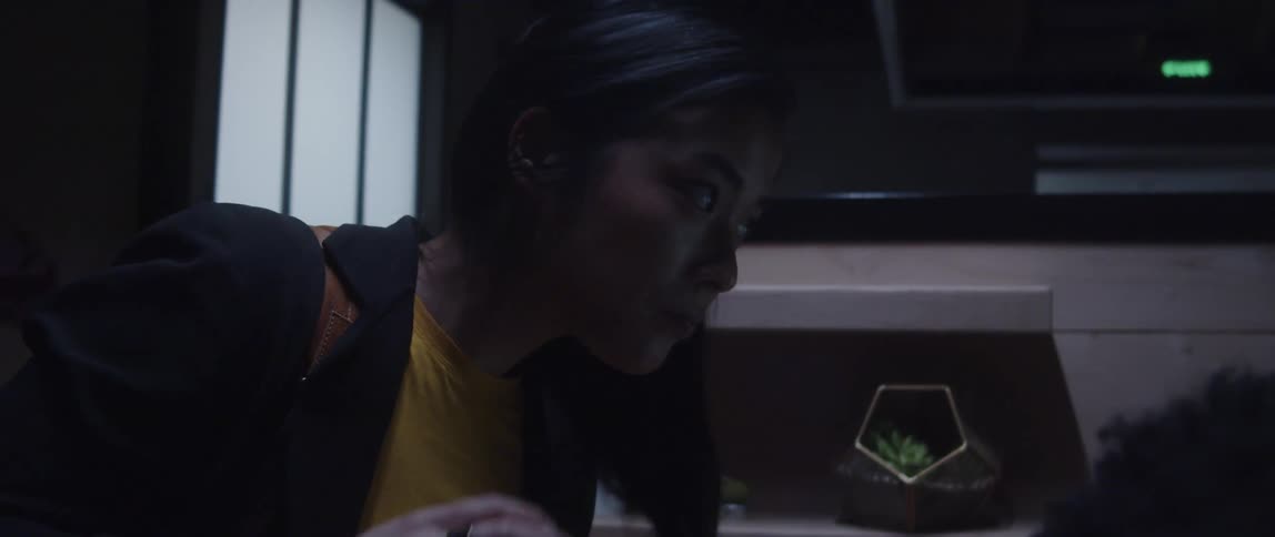 Woman fixes her hair as she leans over to look at coworker's computer in office