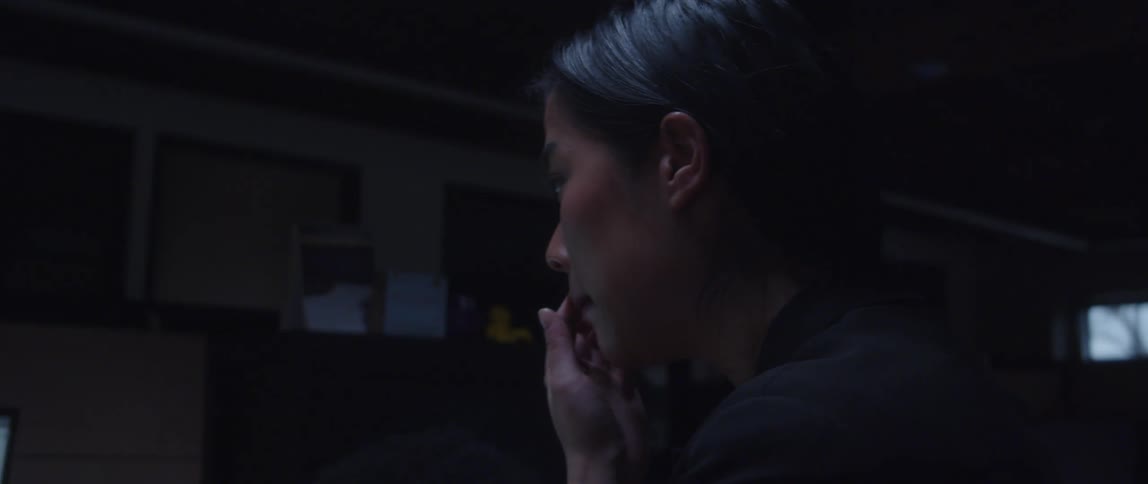 A woman talks to someone off screen in an office cubicle