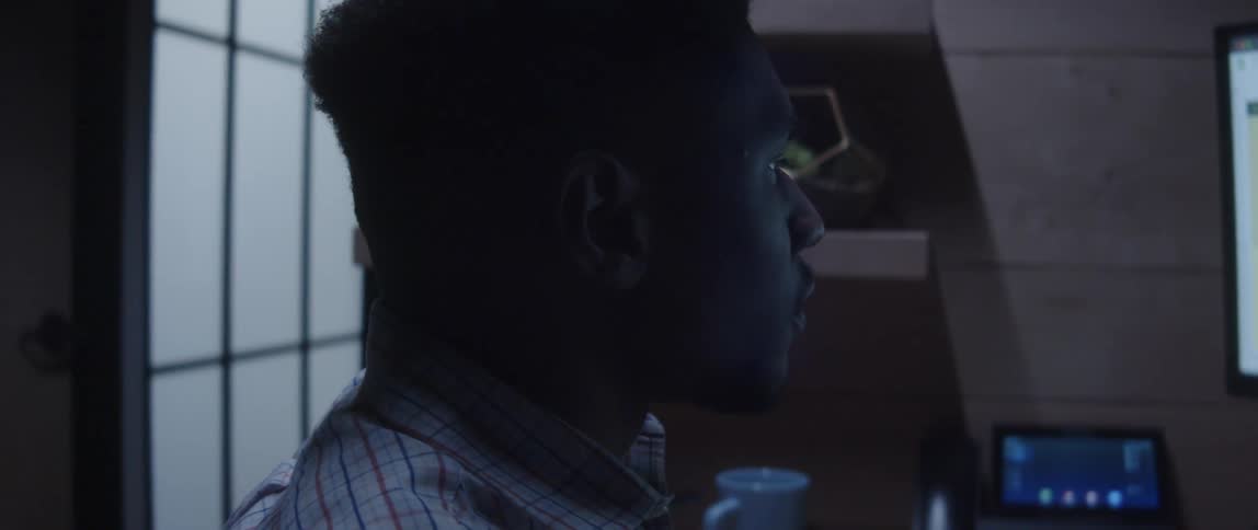 An up close of a mans face looking to the side and then at his computer in front of him