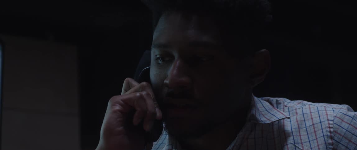 A close up of a man talking on a corded phone making an annoyed expression