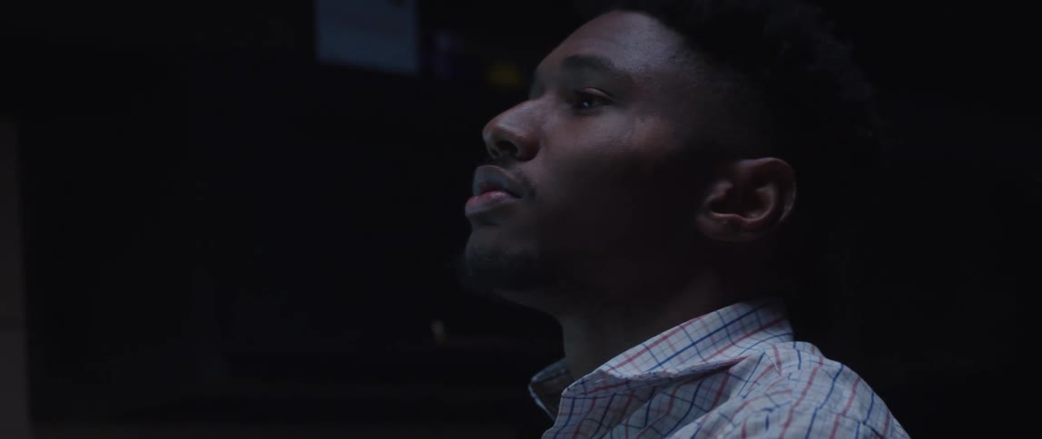 Man leans back while staring upwards in dark area
