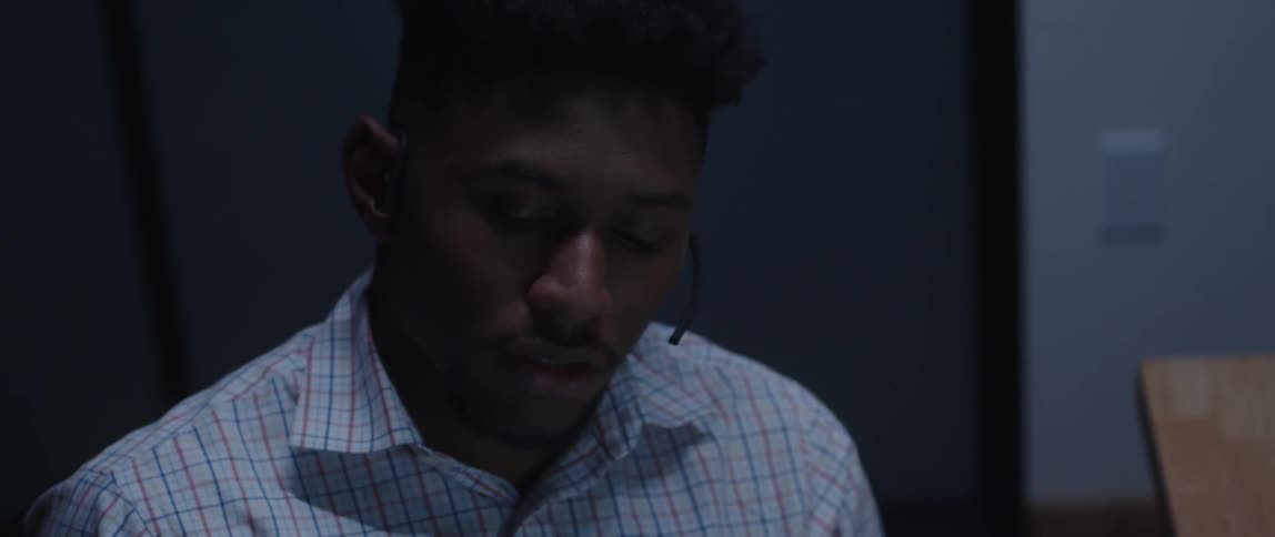 An up close of a man talking on the ear piece phone at a call center