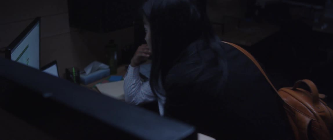A woman helps a colleague with a spreadsheet at his desk
