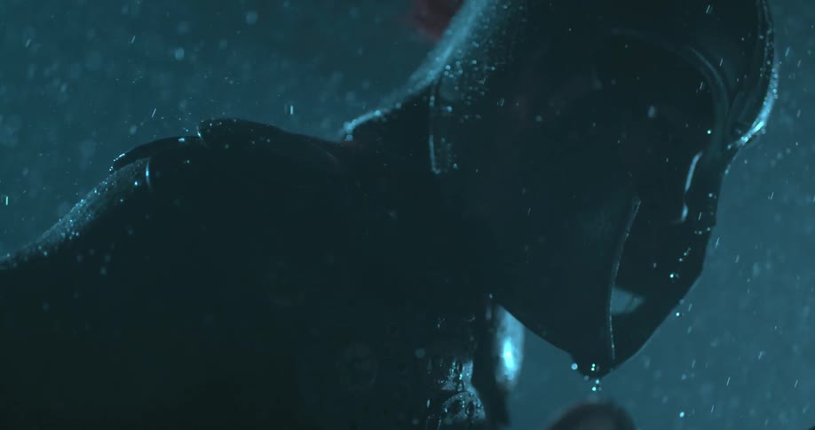 Rain pelts a statue outside at night