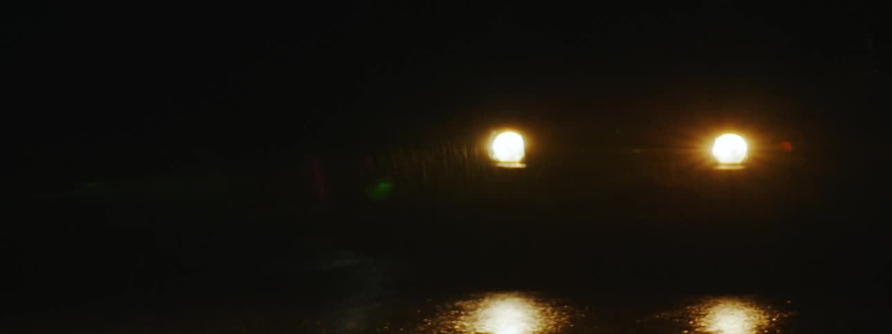 Nighttime Rainy Drive: Car Headlights Illuminate Road