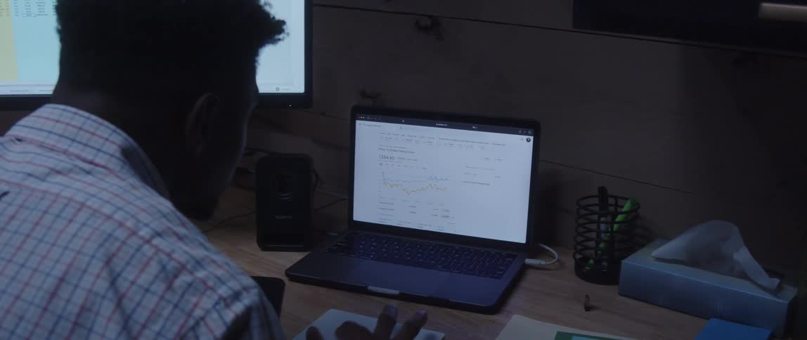 Businessman with shirt sitting at desk uses desktop and laptop at the office