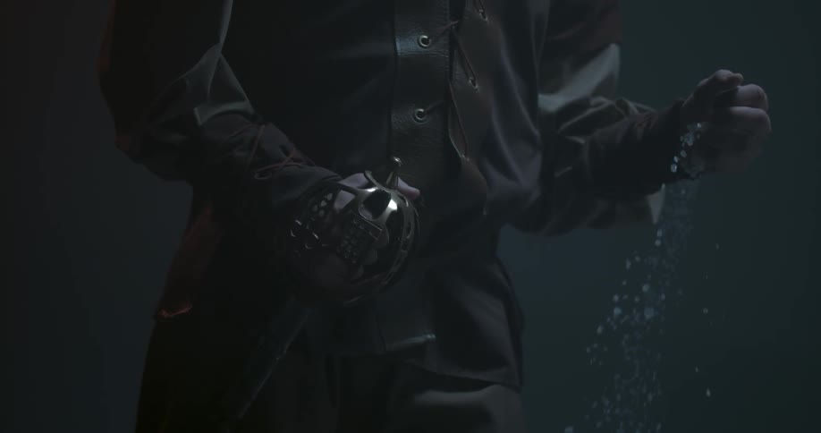 A man holding a sword is letting white rocks slip from his other hand