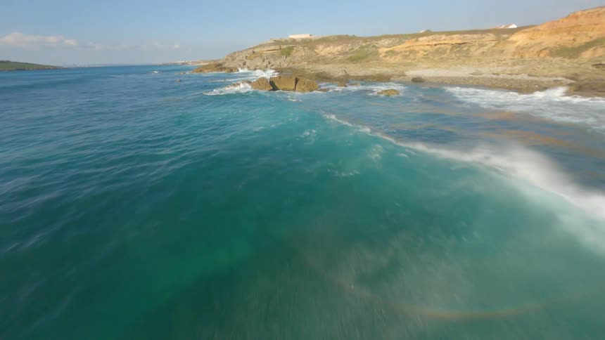 Aerial view of ocean waves breaking against the rocky shore