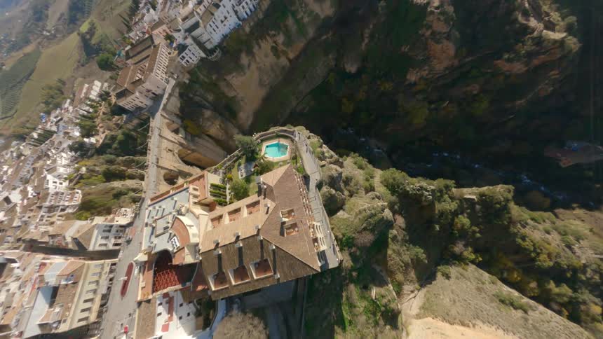 An aerial of a dense city placed next to a large canyon leading to a grassy hillside