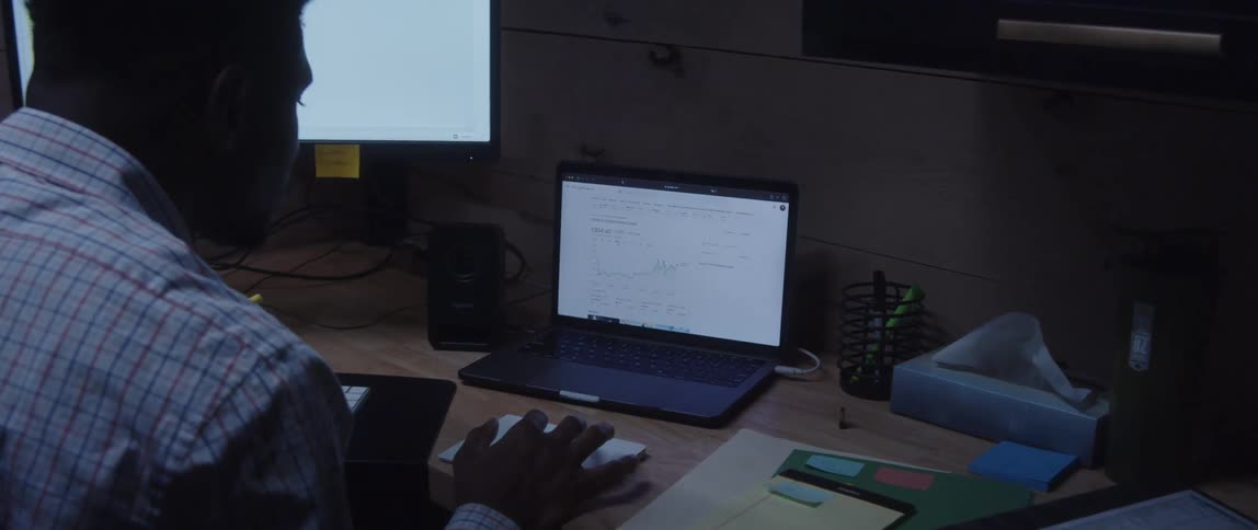 A man works on spreadsheets on two screens
