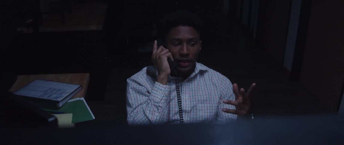 A man is talking on the phone in his office