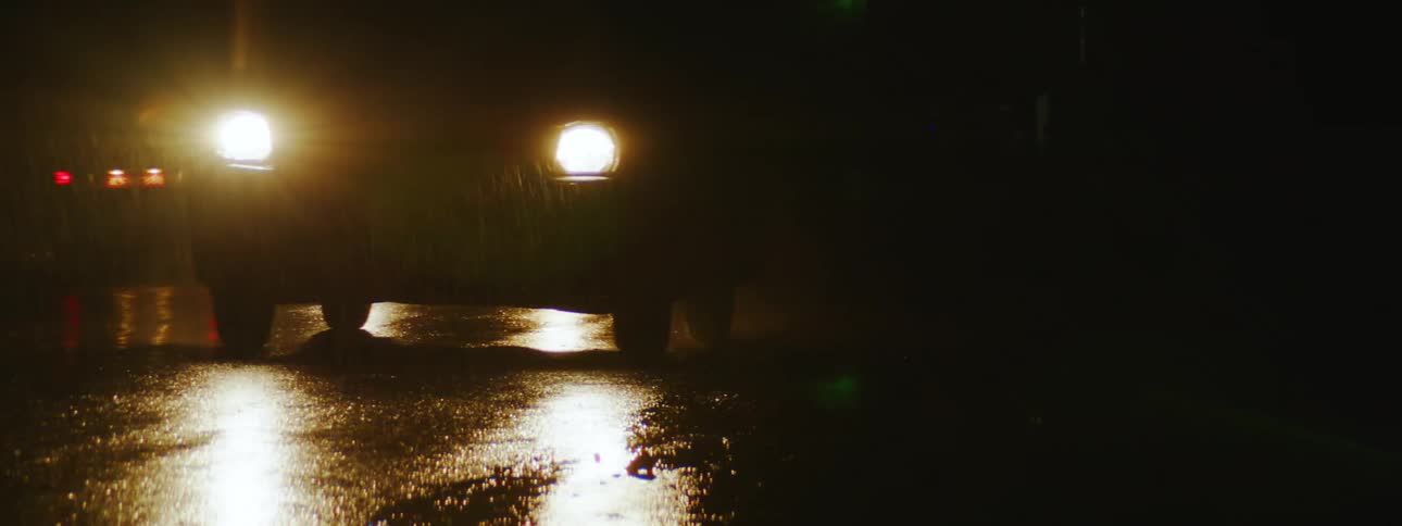 Nighttime Rainy Drive: Car Headlights Reflecting on Wet Pavement