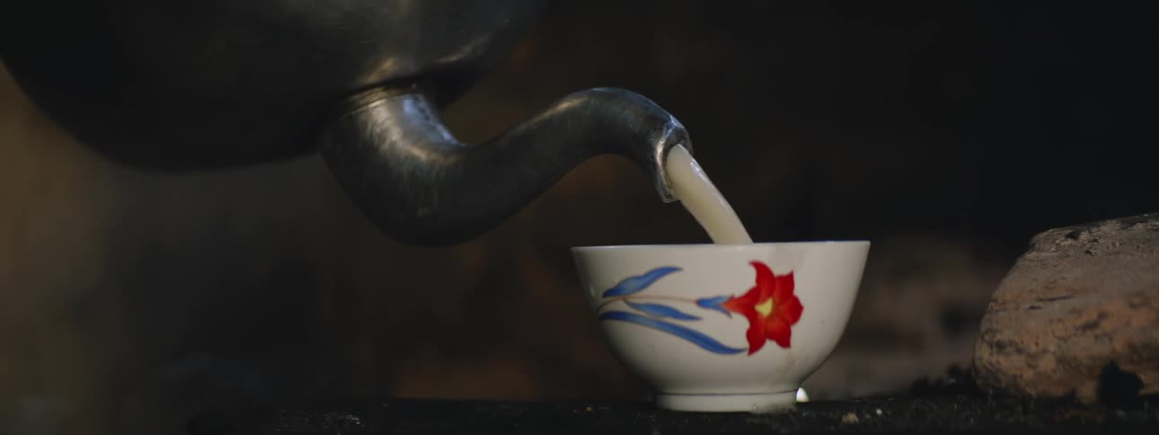 Tea is being poured into a cup with steam