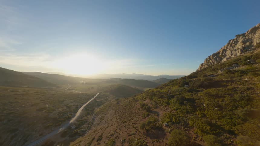 Aerial view of winding road field and mountain at sunset
