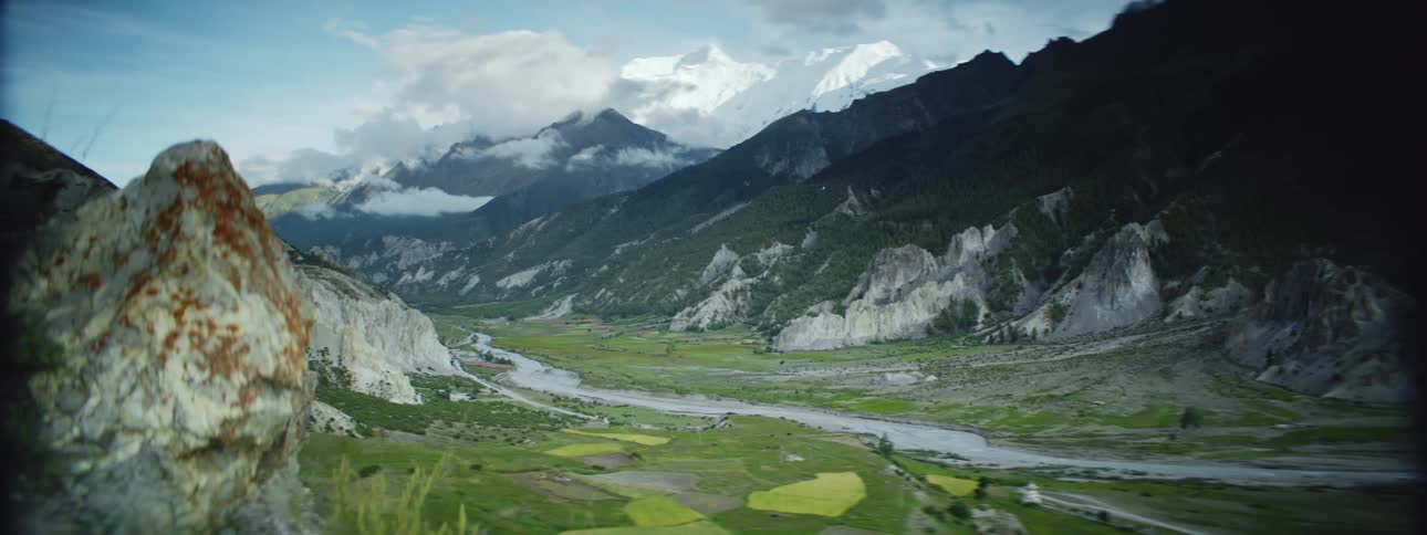 An aerial view of a mountainous landscape with a valley and a river running through it