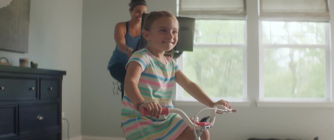 Mother and daughter cycling in a room on stationary bikes