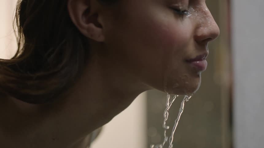 A woman splashes water on her face