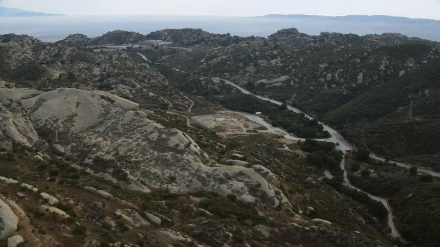 This is a aerial footage of an abandoned aerospace testing facility called Rocketdyne located in Brandeis California with narrow roads wind through a vast canyon during daytime