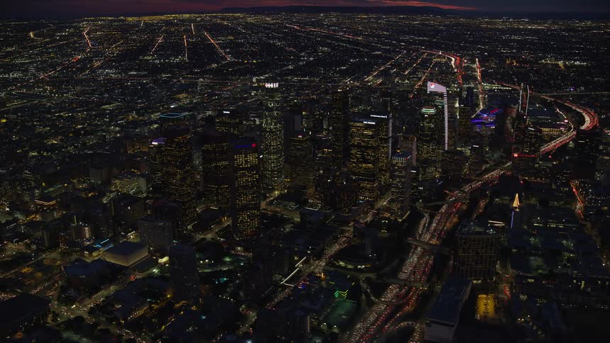 A stunning night-time panoramic view of Downtown Los Angeles with lit-up skyscrapers towering over the cityscape