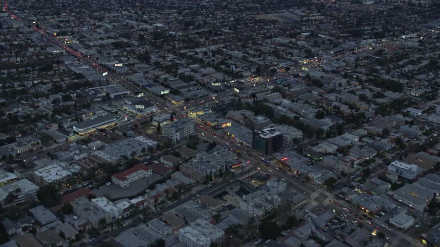 Aerial view of busy businesses and residential areas along La Cienega Boulevard and West Pico Blvd at twilight in central Los Angeles