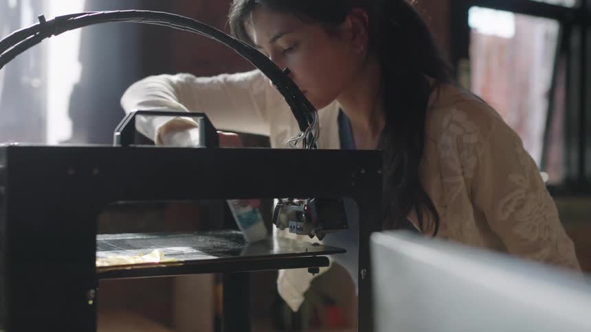 A woman is cleaning the 3d printer