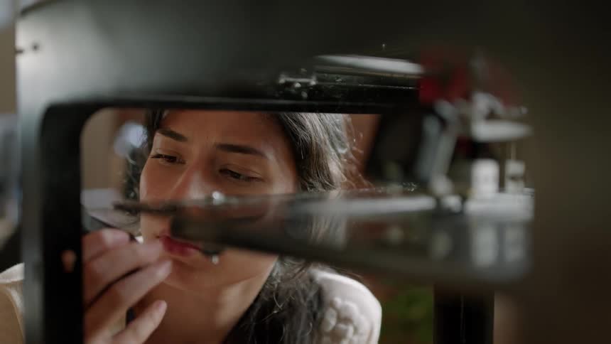 Woman examines machine moving arm across platform while she holds object