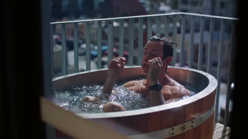 A man plunges himself into a large ice bath on the patio of his apartment