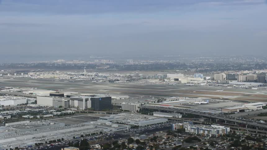 This clip showcases an aerial view of Los Angeles International Airport on a cloudy day as it gets closer to the airport