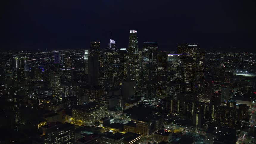 Aerial shot of Downtown Los Angeles skyscrapers and City Hall at night during summertime