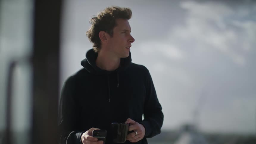 A man is standing outdoors and texting on his phone