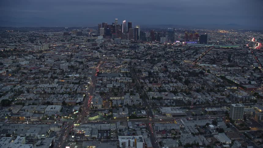 Aerial shot of downtown Los Angeles skyline during twilight showcasing the citys high rise buildings skyscrapers and superstructures from different perspectives