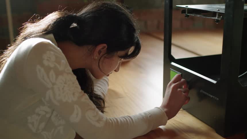A woman sits on the floor and turns a dial back and forth on a contraption of some sort