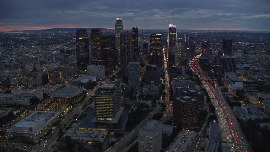 A beautiful aerial shot of tall skyscrapers during twilight in Downtown Los Angeles California with partly cloudy skies